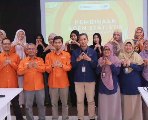 Foto bersama narasumber dari BPS, dosen FAST UAD, dan mahasiswa peserta Pembinaan Agen Statistik Tahap V di Universitas Ahmad Dahlan Yogyakarta. Peserta berpose dengan simbol tangan segitiga di depan layar proyektor.
